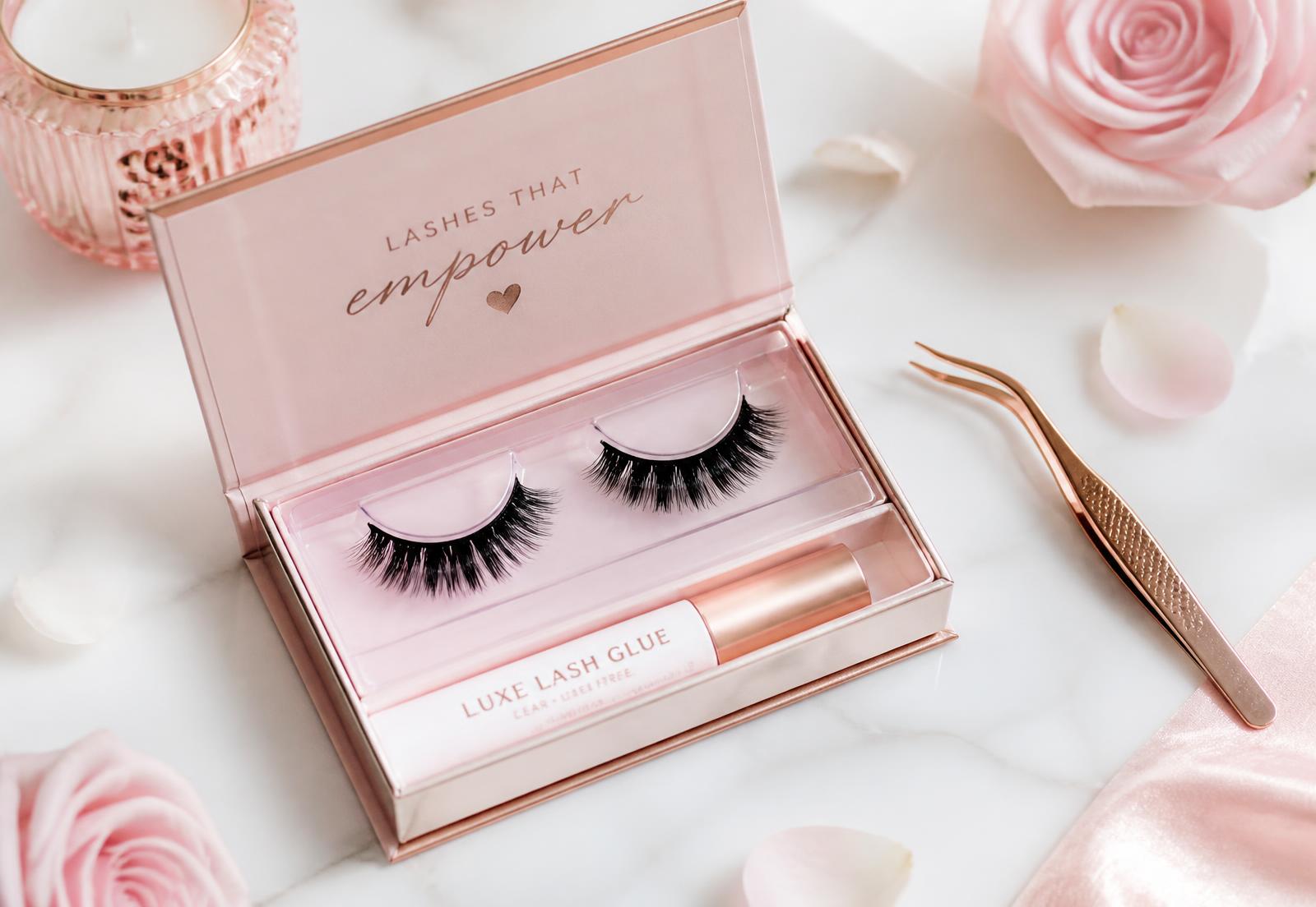 Rose gold false eyelash kit with tweezers and lash glue on marble